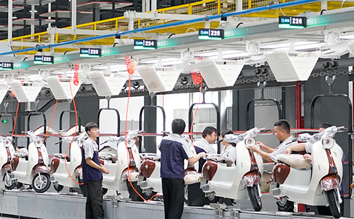 Workers assembling electric scooters on a production line in a modern factory setting, showcasing advanced manufacturing processes and quality control.