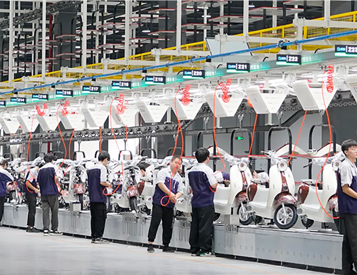 An image of a modern manufacturing assembly line where workers are assembling electric scooters in a factory setting, showcasing industrial automation and production efficiency.